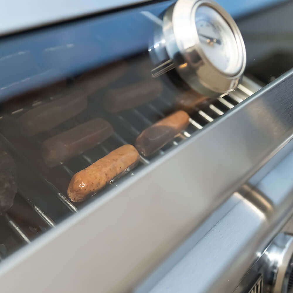 Grilled sausages on a barbecue with a thermometer inserted.
