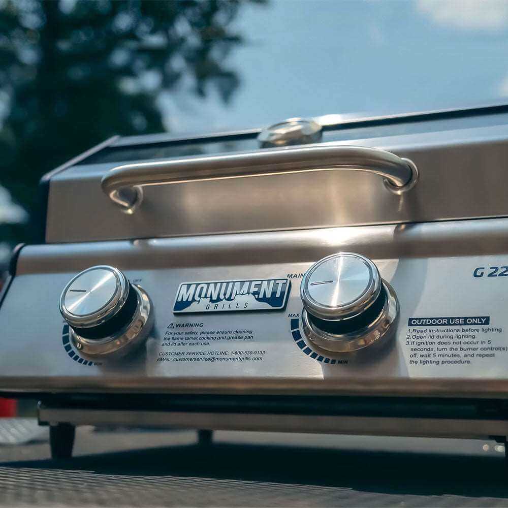 Close-up of a stainless steel grill with 'Monument Grills' branding.