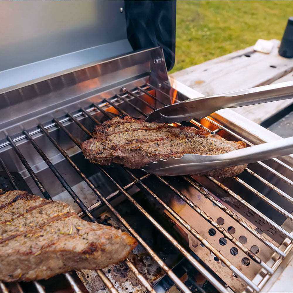 Steaks being grilled on a barbecue with tongs
