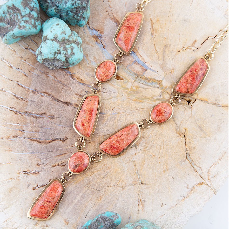 Necklace with coral-colored stones on a textured surface