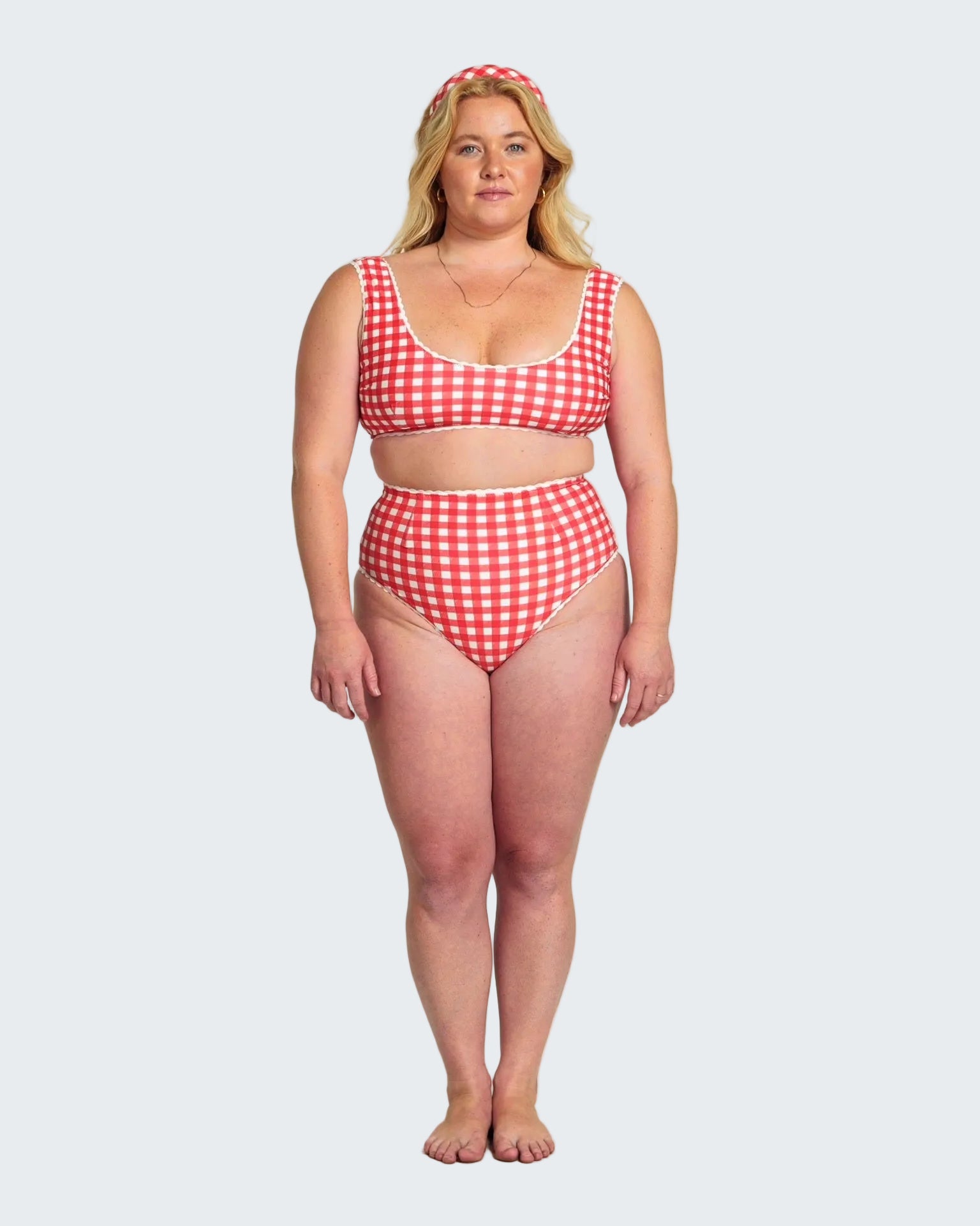 Woman wearing a red and white checkered bikini on a plain background