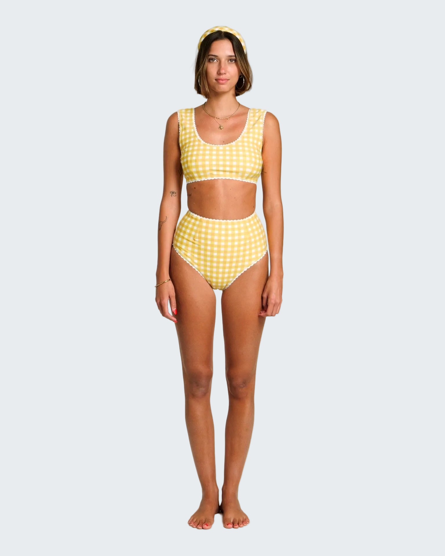 Woman wearing a yellow checkered bikini set on a white background
