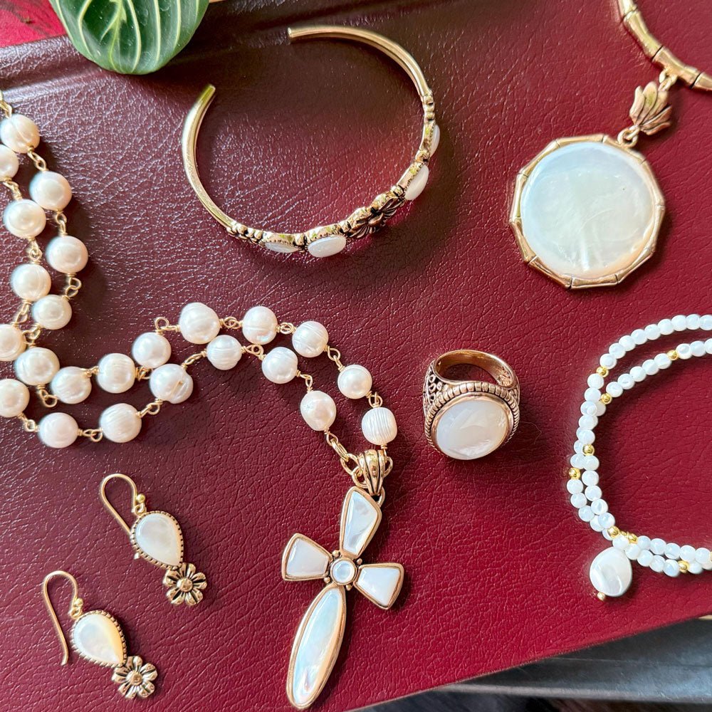 Collection of gold and pearl jewelry on a red surface