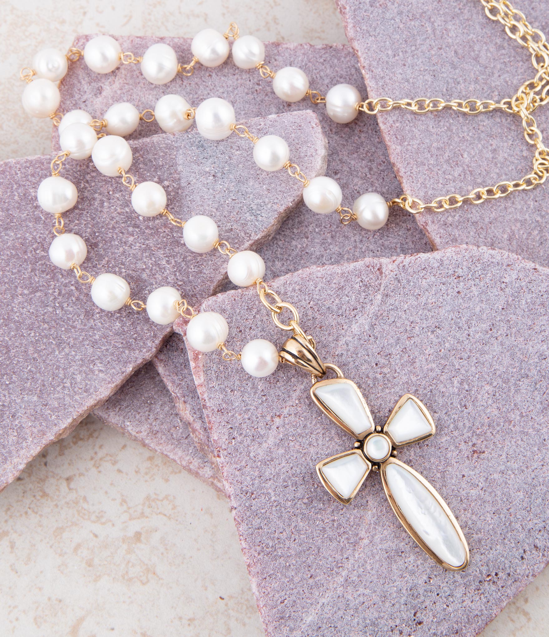 Pearl necklace with a cross pendant on a textured surface