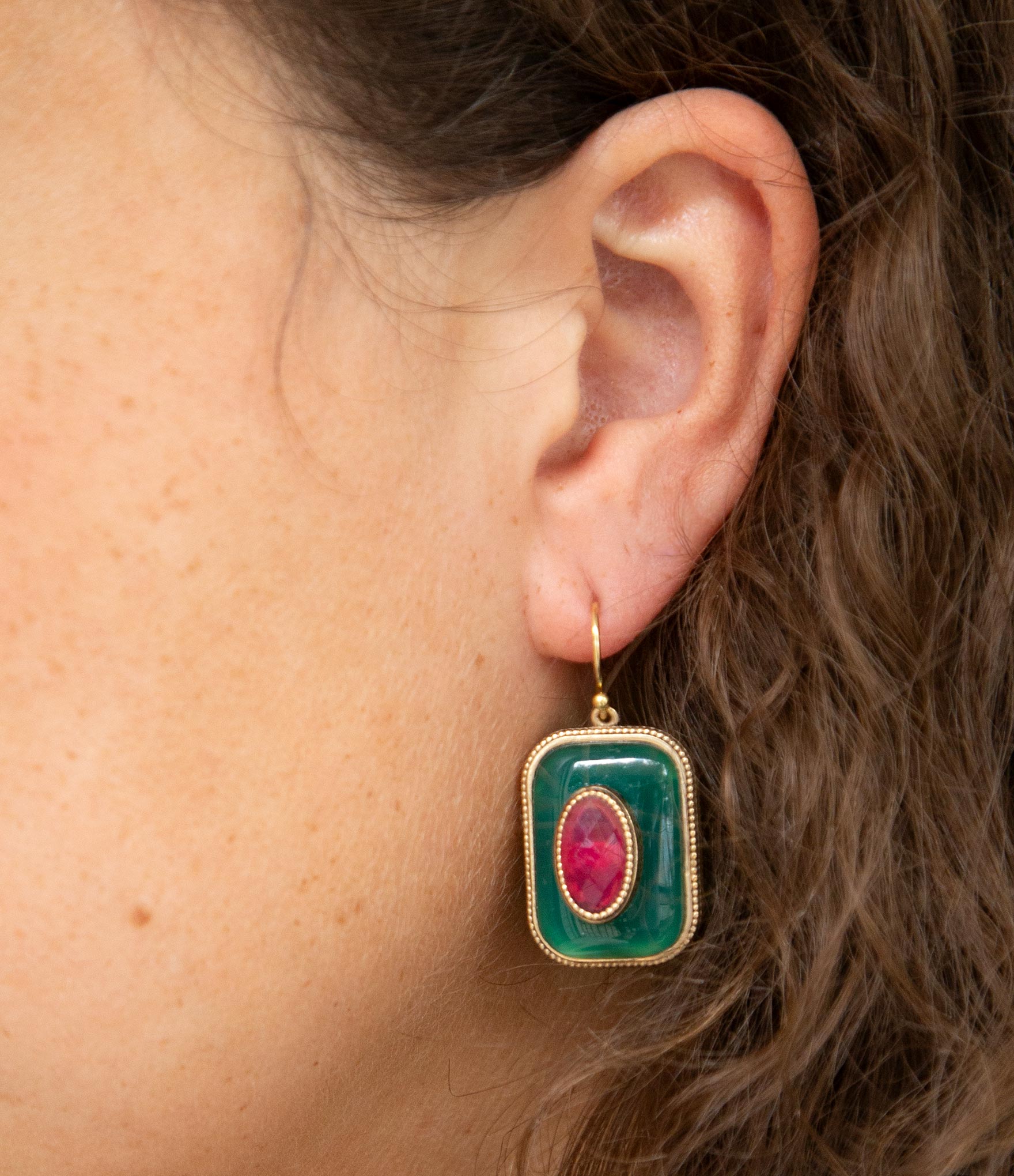 Close-up of an ear wearing a green and pink earring.