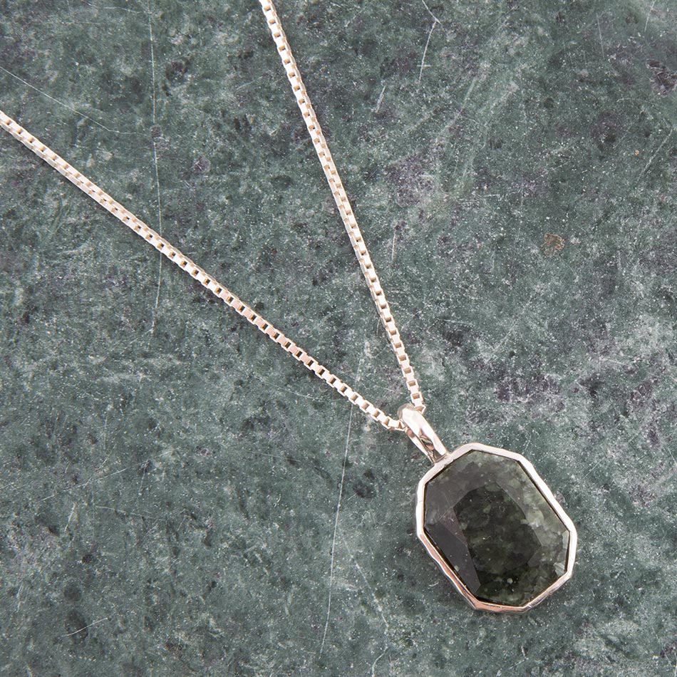 Necklace with a green stone pendant on a green marble surface