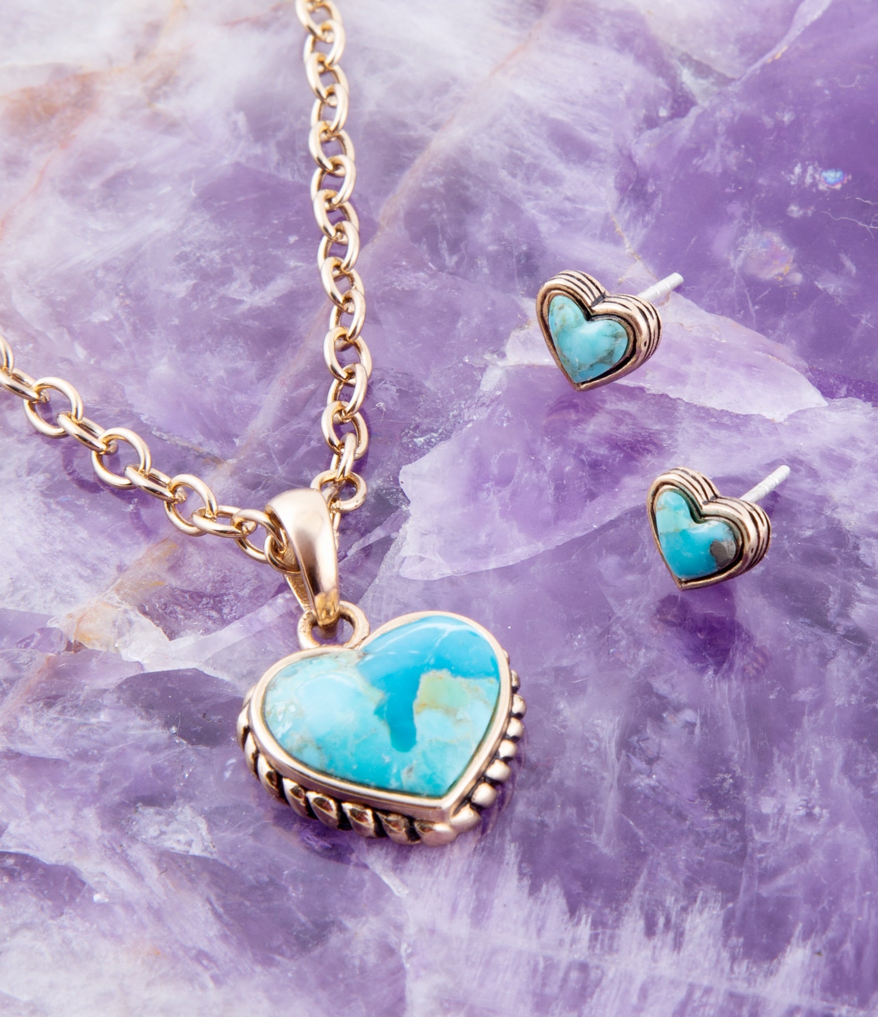 Turquoise heart-shaped jewelry set on a purple stone background