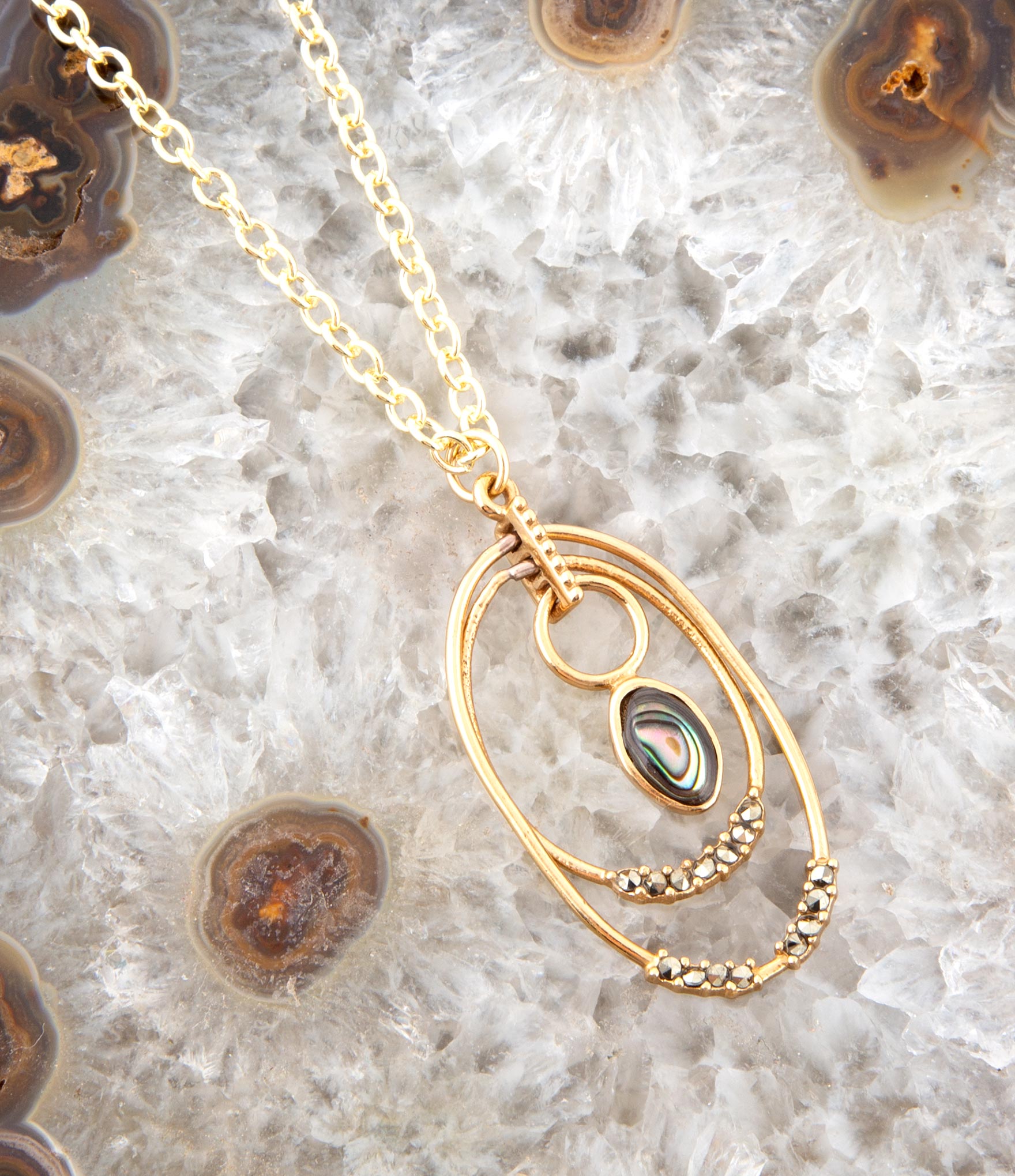 Gold necklace with a pendant on a textured stone surface