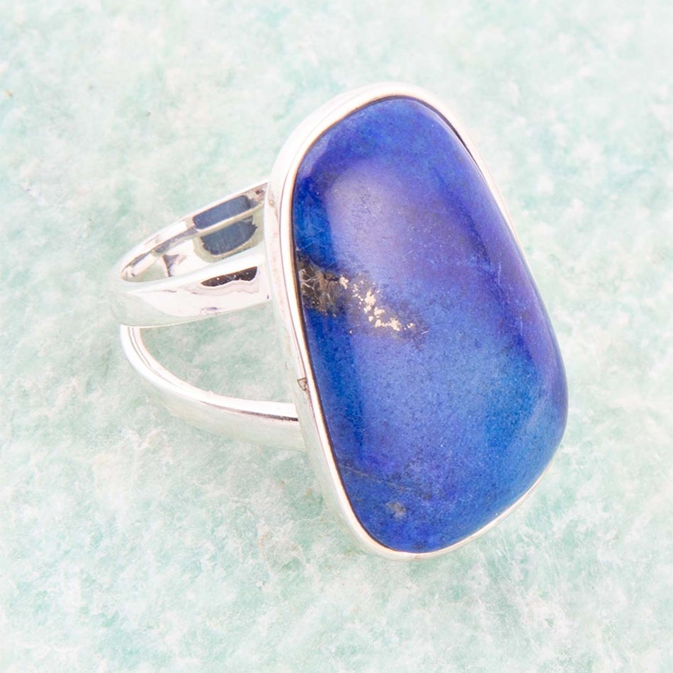 Silver ring with a large blue stone on a light green background