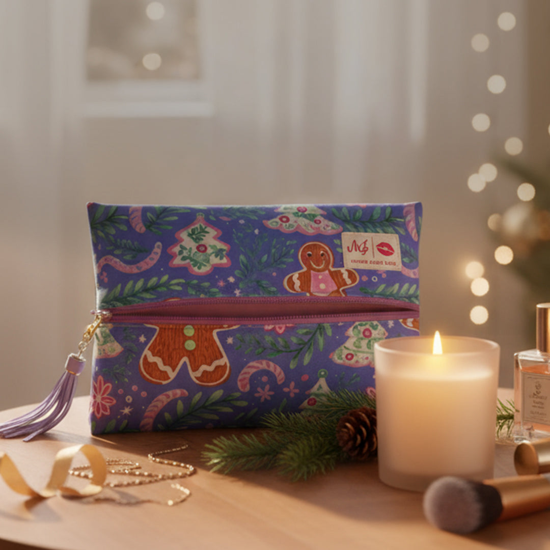 Colorful makeup bag with gingerbread design on a table with a candle and perfume bottle.