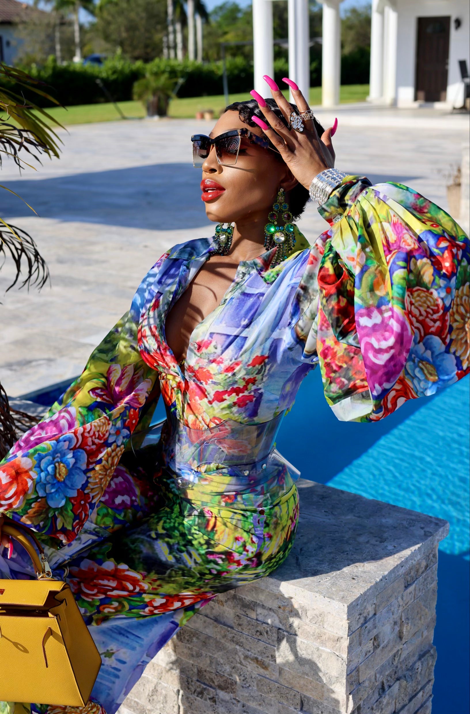 Woman in a colorful floral dress sitting by a pool