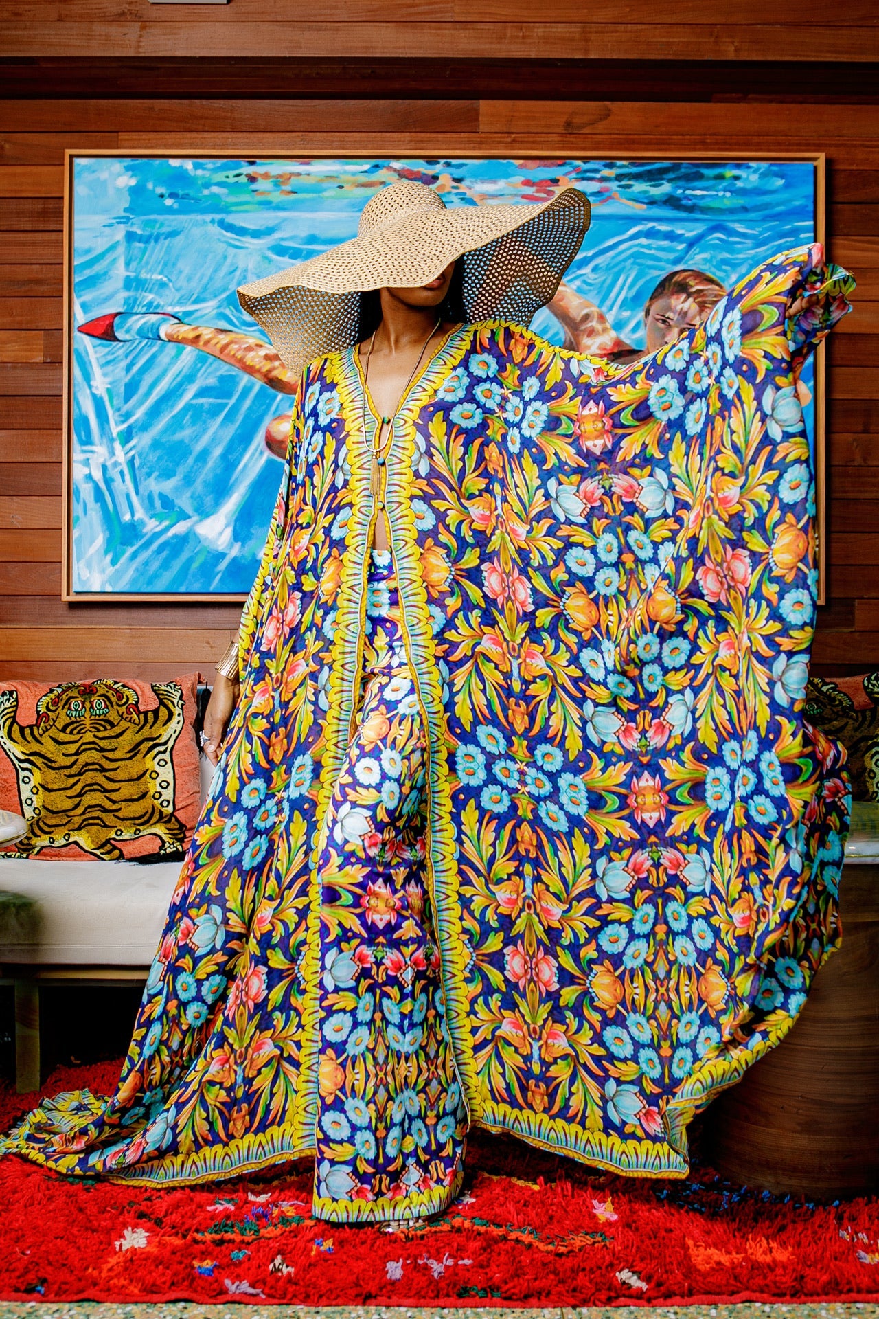 Person wearing a colorful floral dress in a room with a painting on the wall.