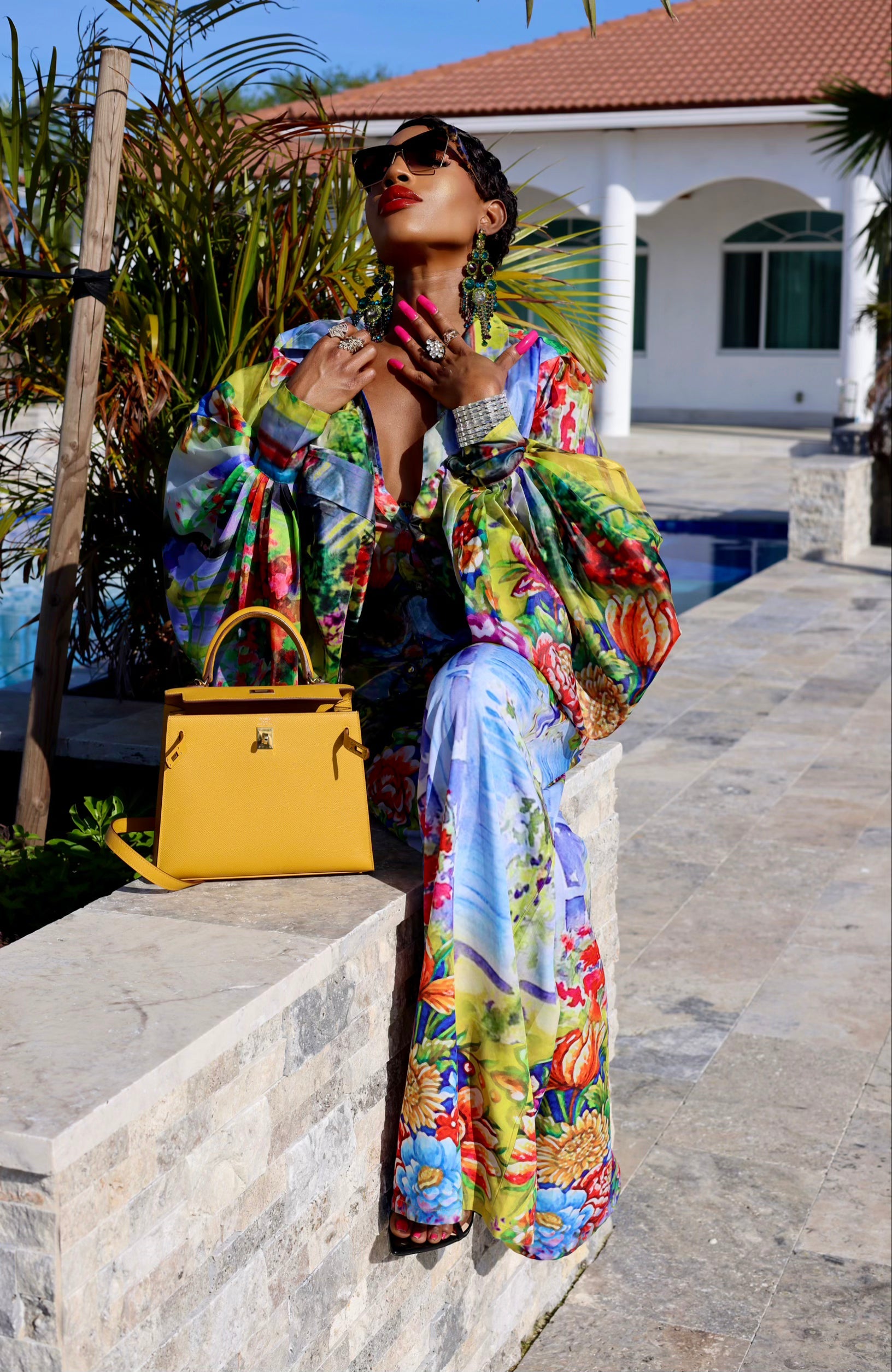 Woman in colorful outfit with yellow handbag by poolside