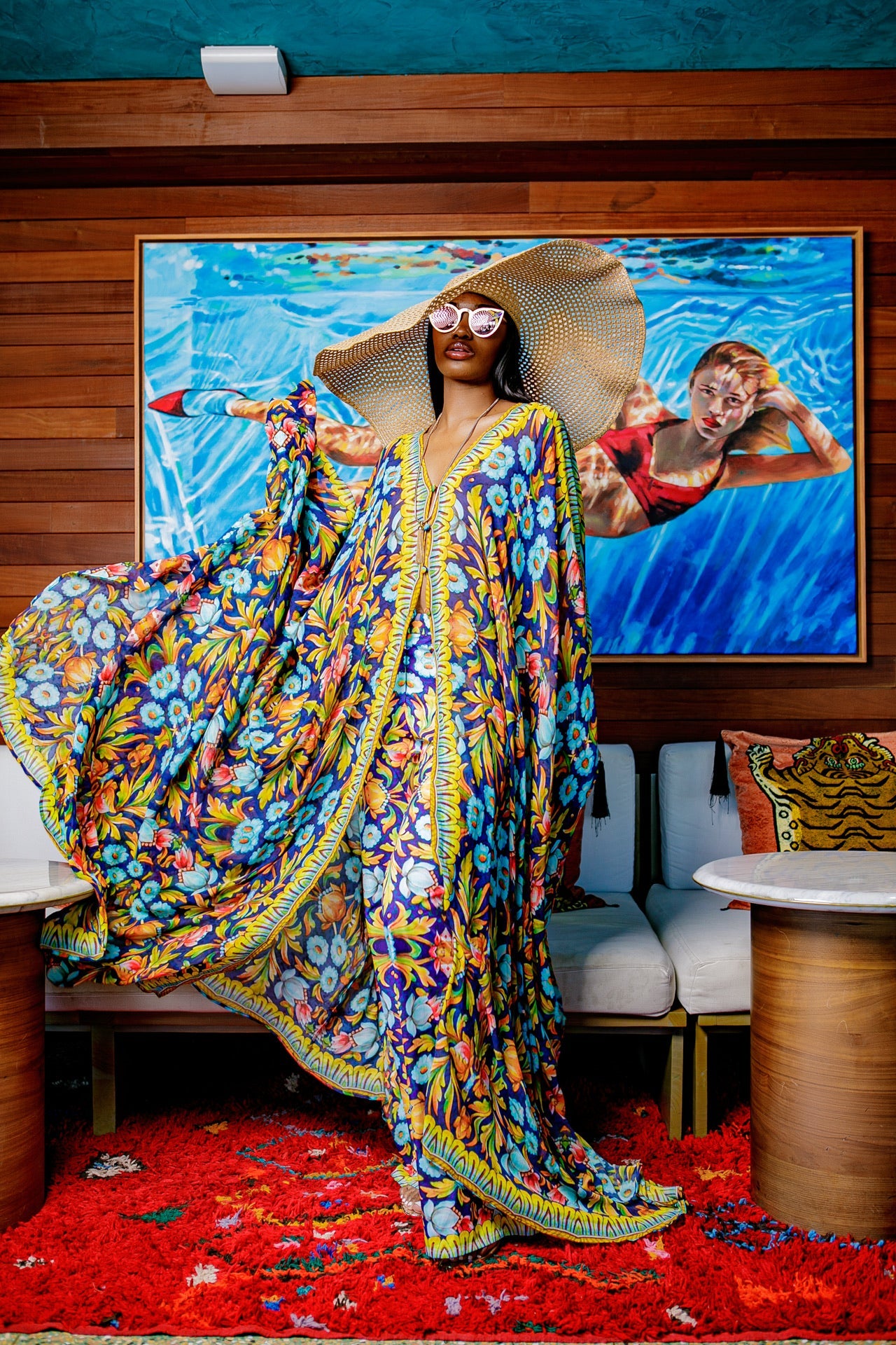 Woman in a colorful dress standing in a room with a large painting on the wall.
