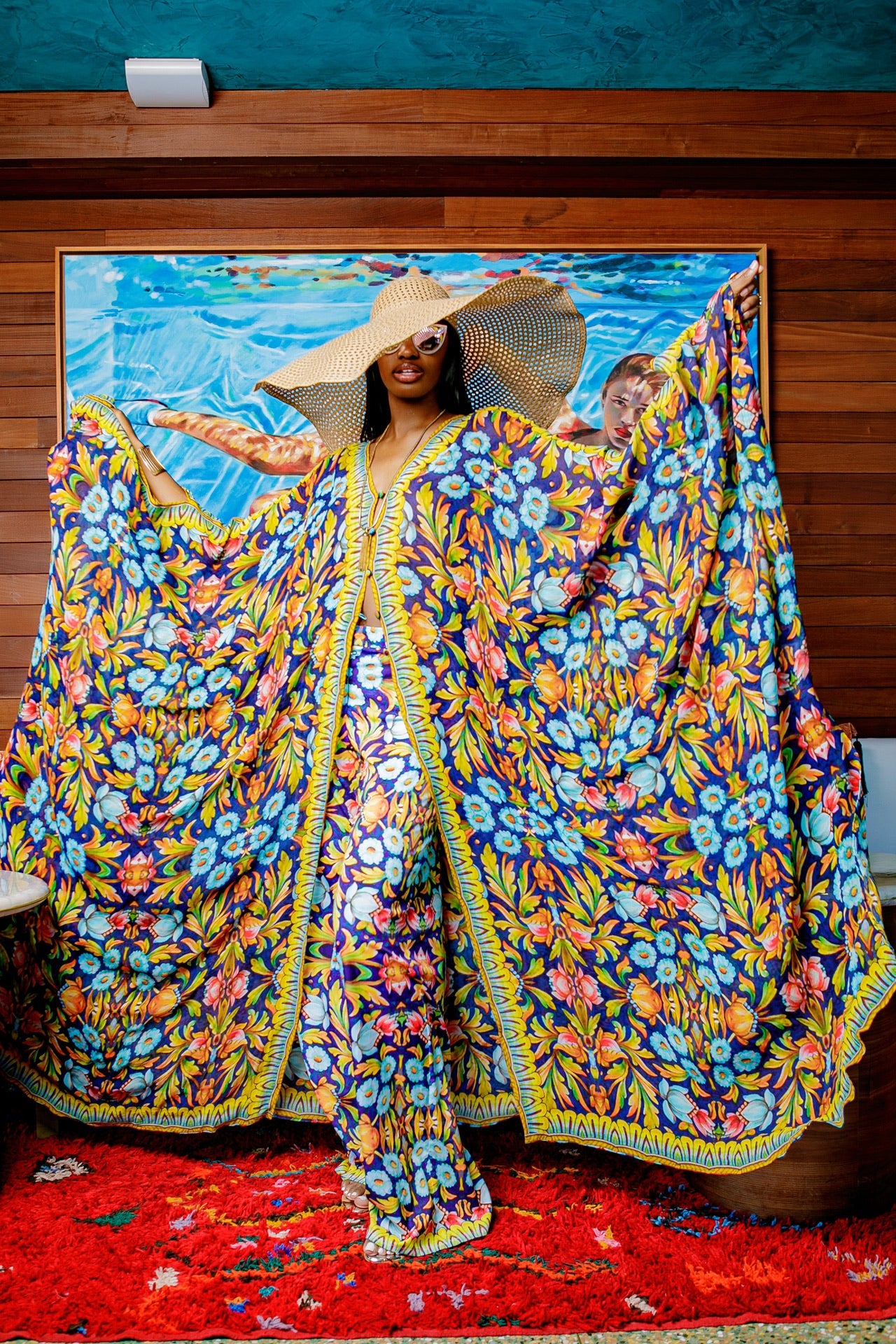 Woman wearing a colorful floral outfit with a large painting in the background