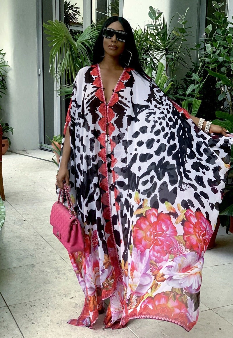 Woman wearing a colorful floral and animal print dress with sunglasses and a pink handbag.