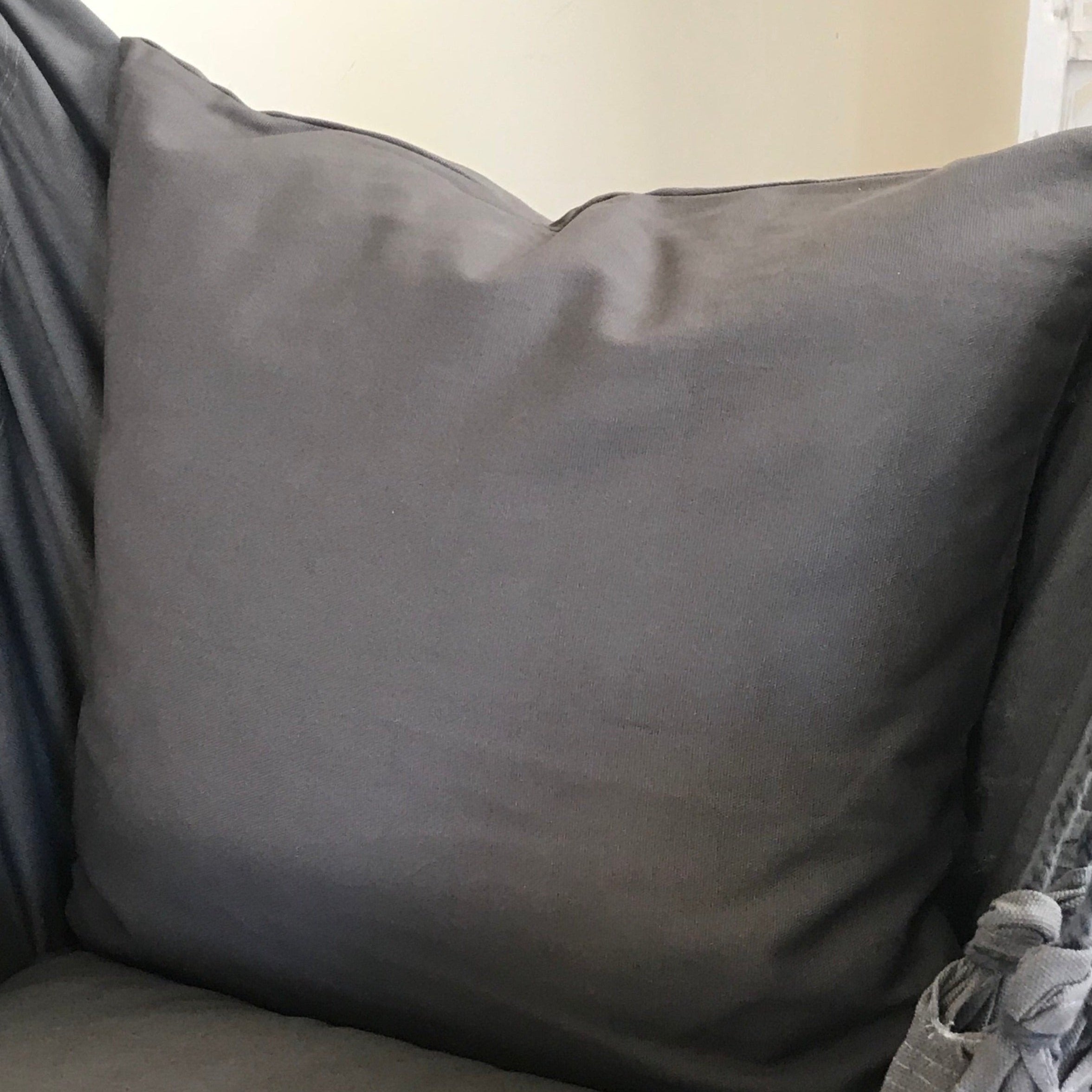 Gray pillow on a sofa with a neutral background