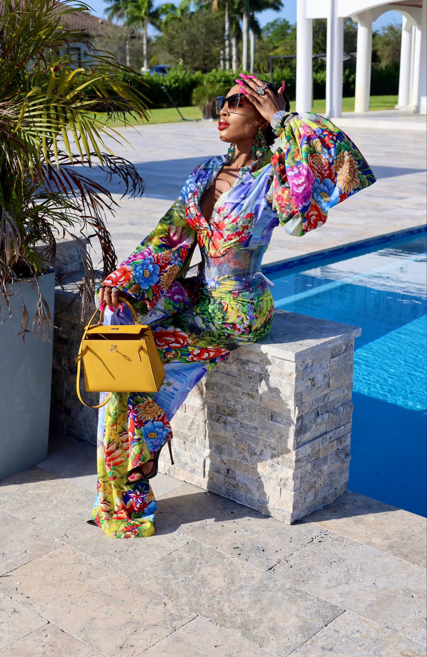 Woman in a colorful outfit sitting by a poolside