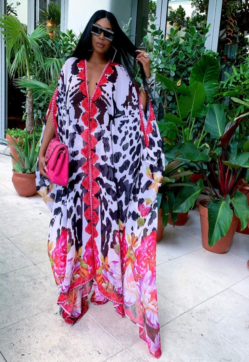 Woman wearing a colorful floral dress with a pink handbag in an outdoor setting.
