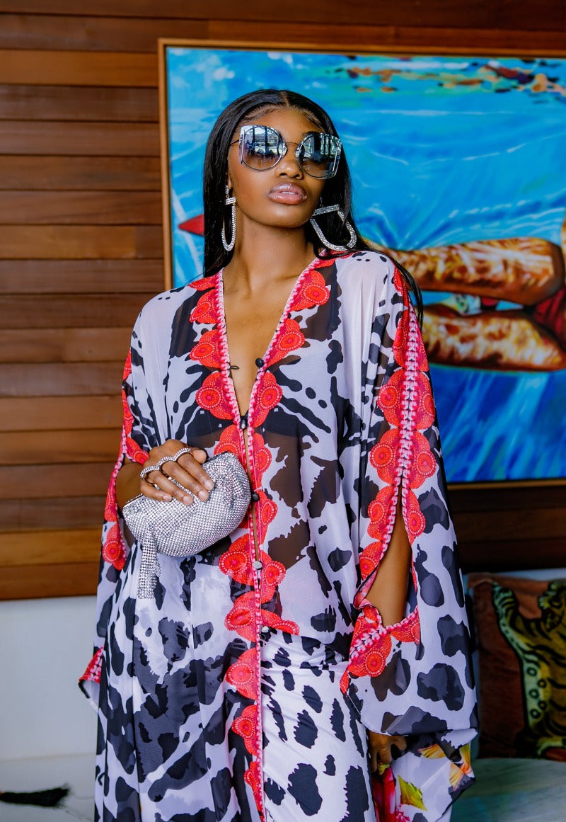 Woman wearing a patterned outfit with sunglasses in front of a colorful painting