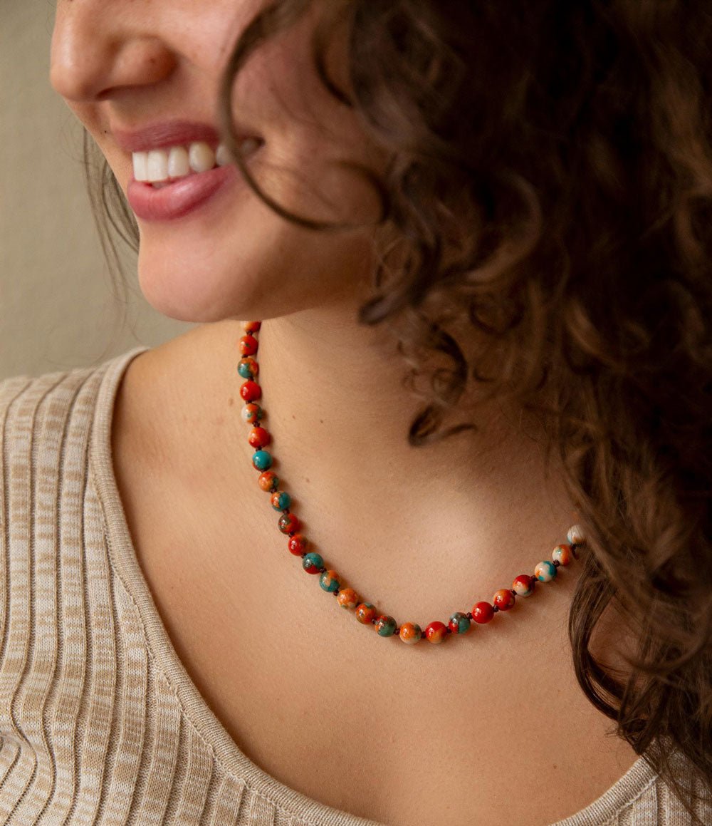 Woman wearing a colorful beaded necklace with a neutral background