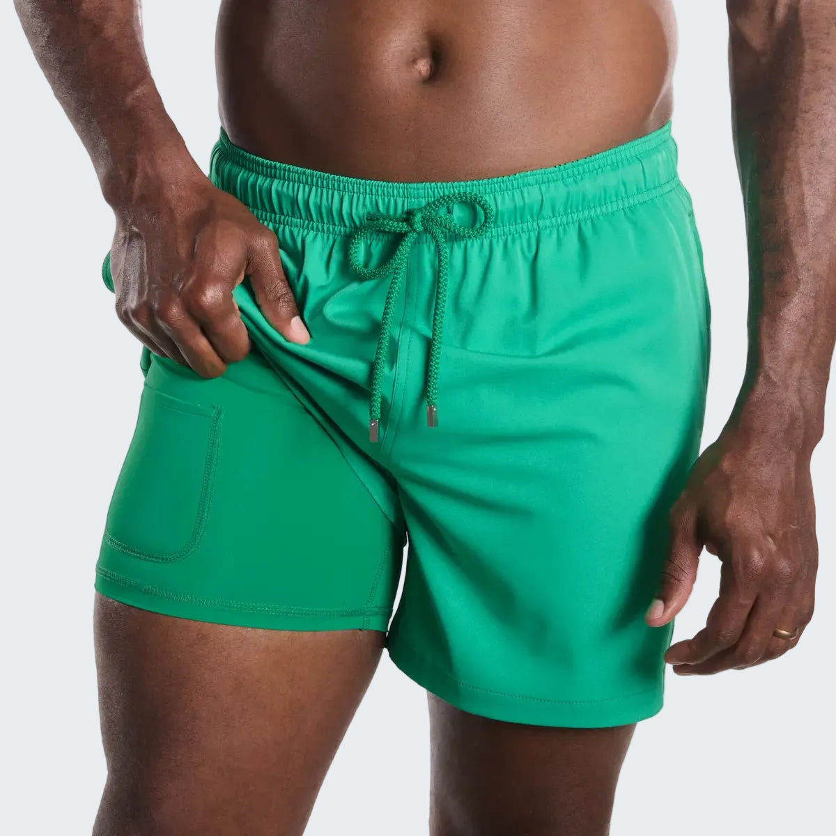 Green swim shorts worn by a person on a white background