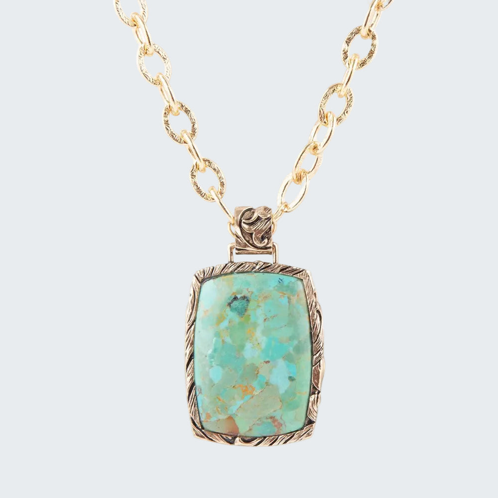 Turquoise pendant necklace on a gold chain against a white background