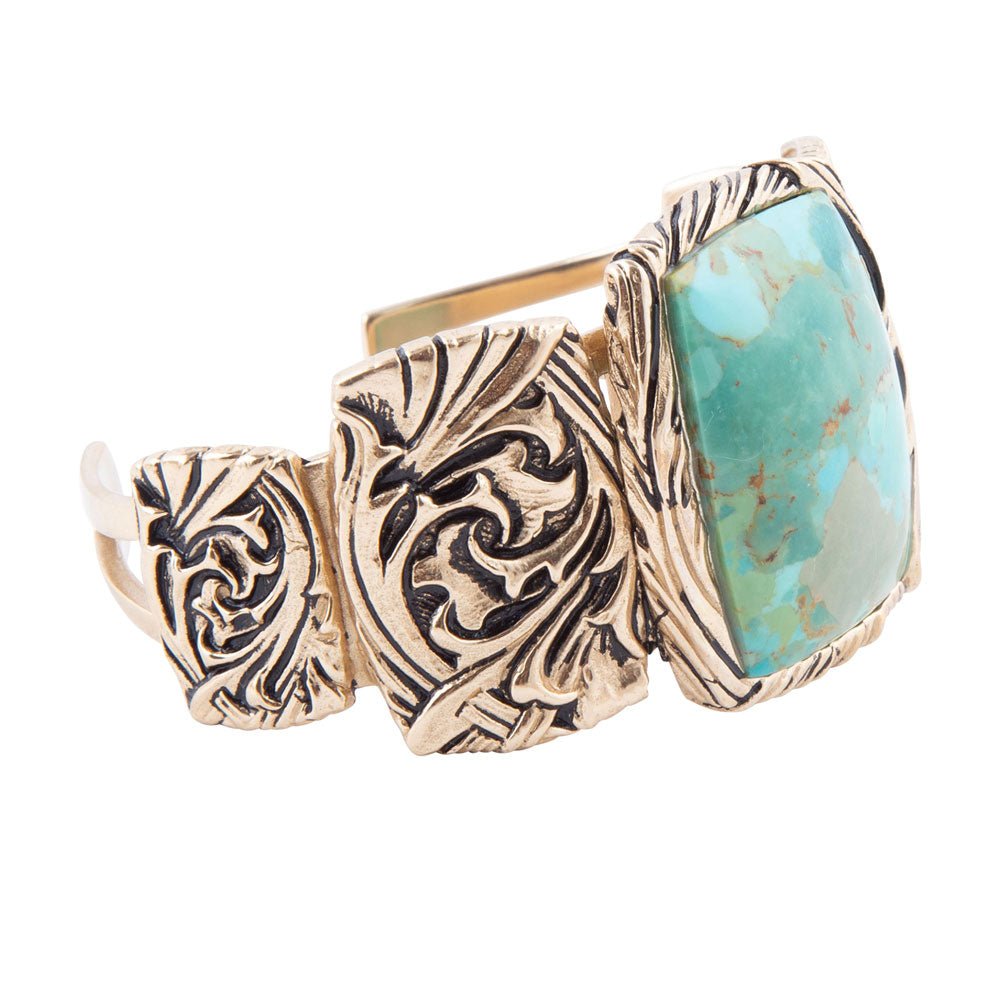 Gold and turquoise ring with intricate design on a white background