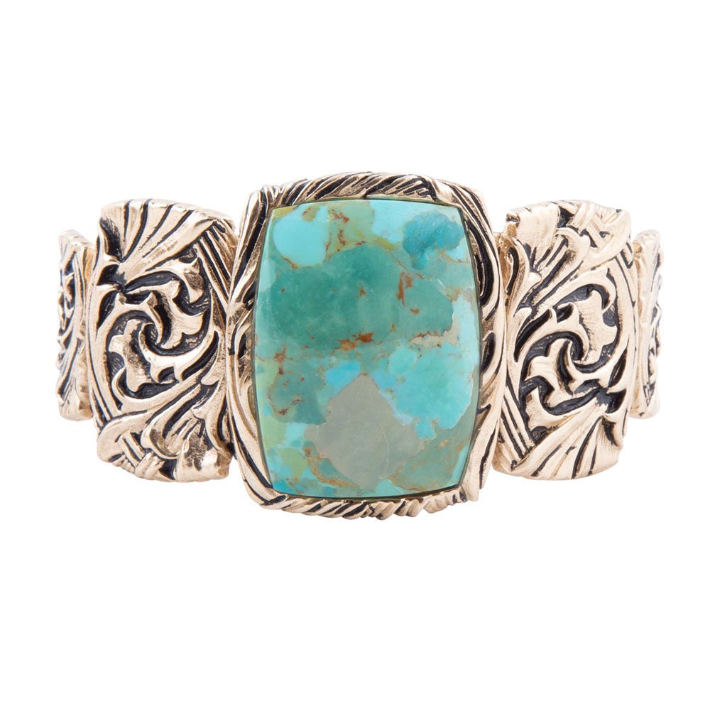 Cuff bracelet with turquoise stone and gold-tone metalwork on a white background