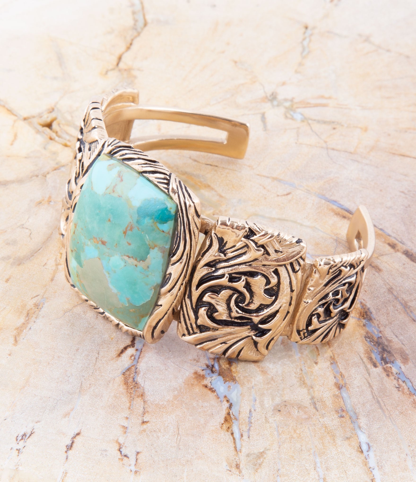 Bronze bracelet with turquoise stone on a beige marble background