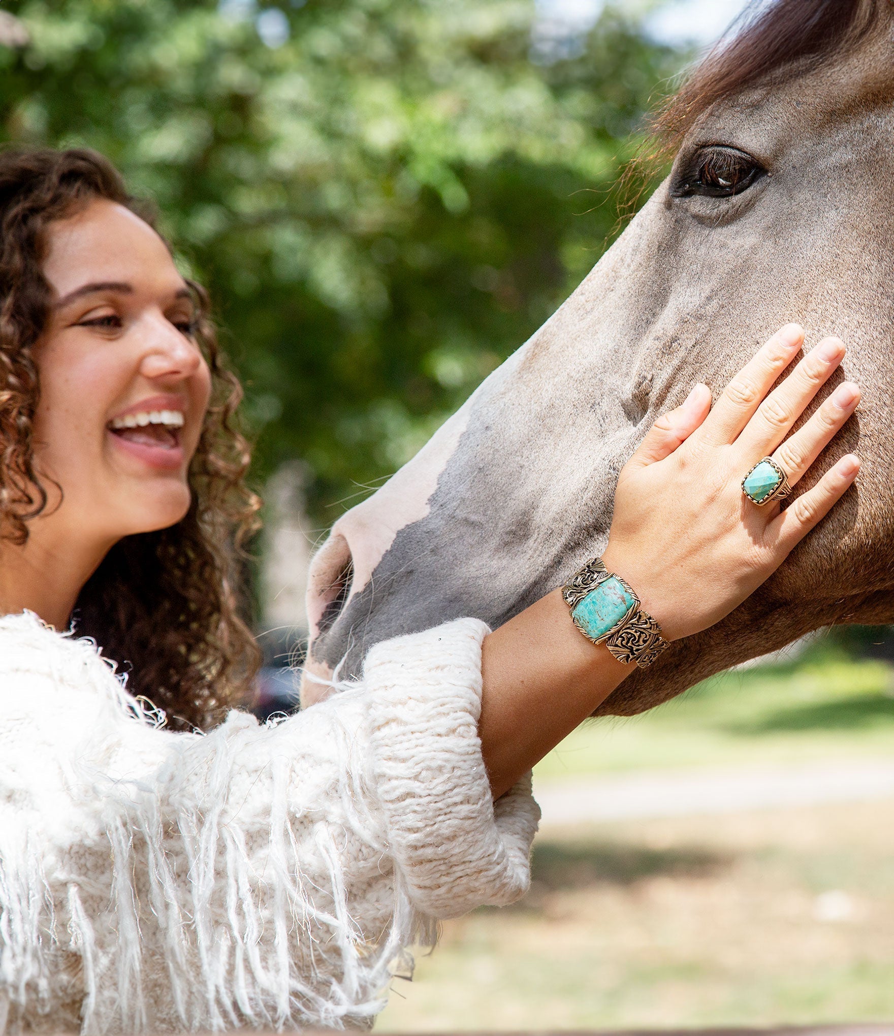 Woman with turquoise ring petting a horse outdoors