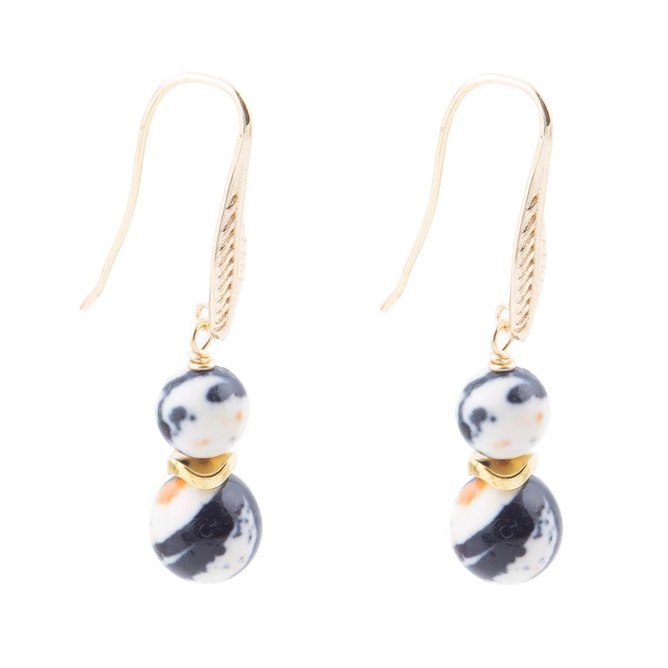 Pair of earrings with gold hooks, black and white marbled beads on a white background