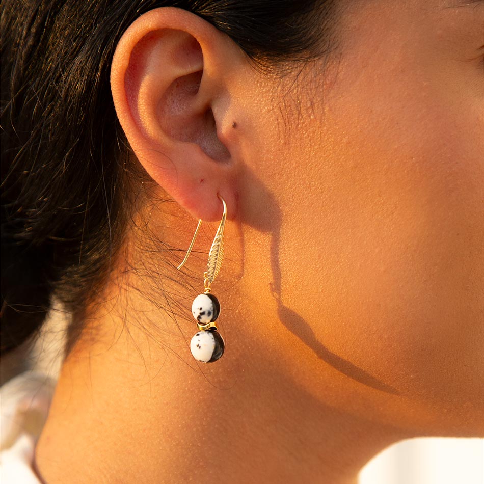 Close-up of an ear wearing a gold earring with a small white bead.