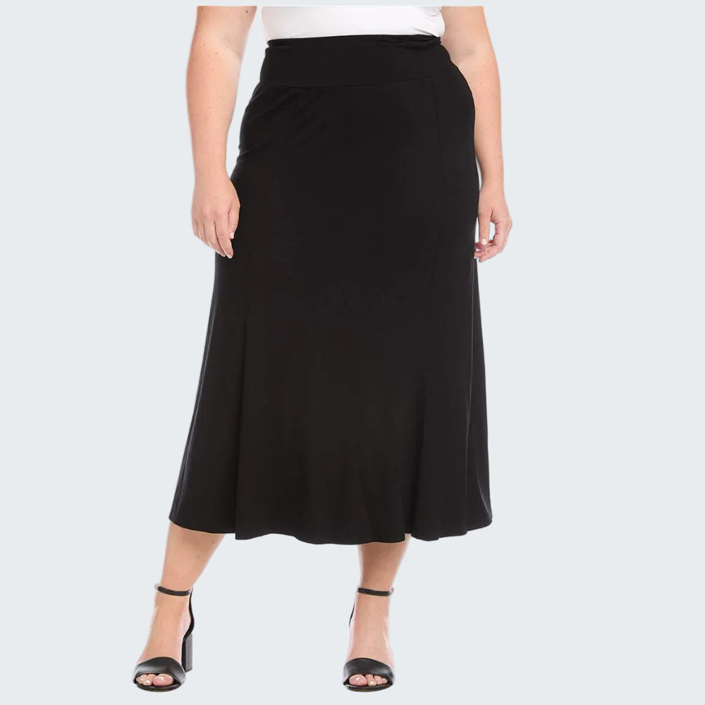 A woman modeling a black midi skirt with a flared silhouette, paired with a white top and black heeled sandals, against a plain white background.
