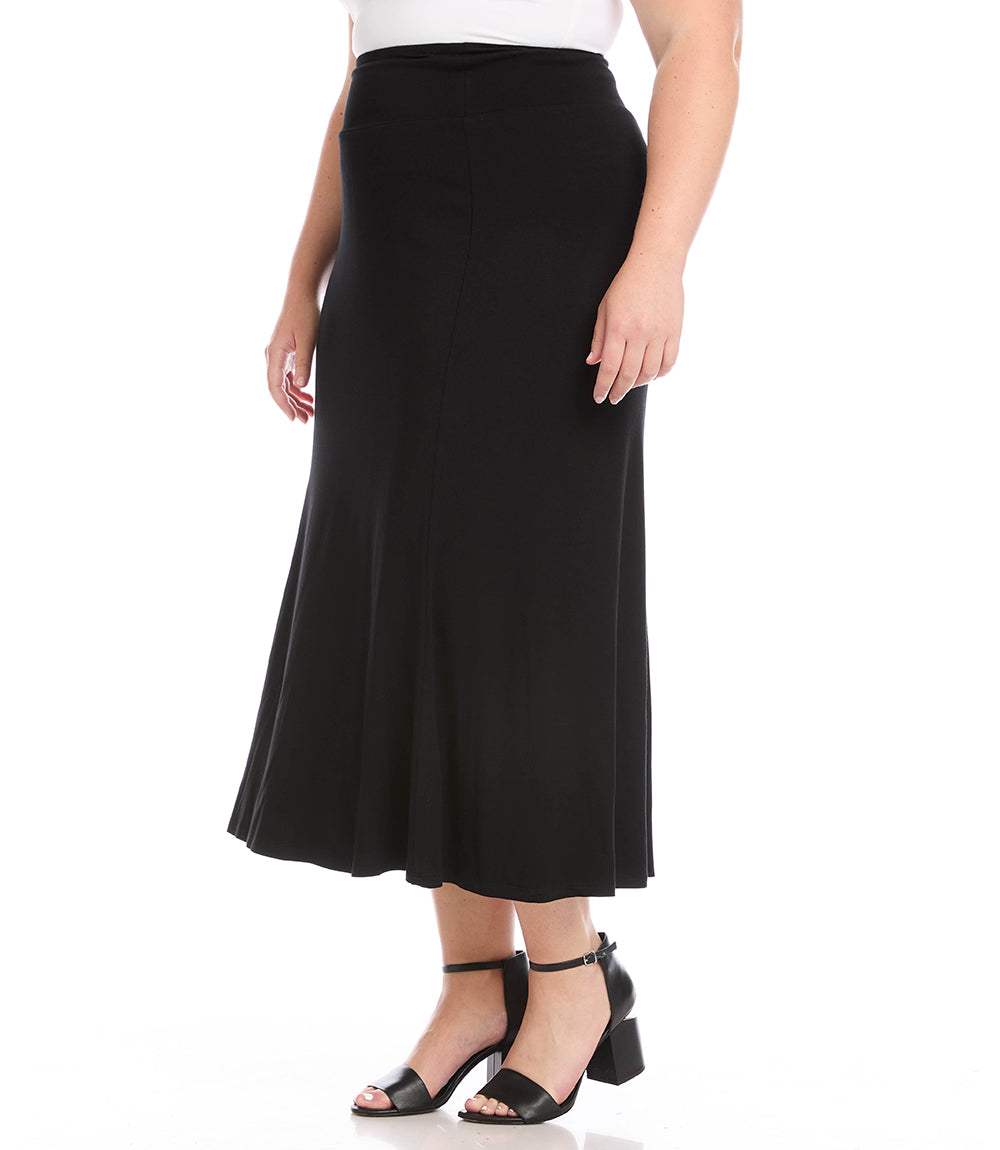 A black midi skirt worn by a model, paired with a white top and black block-heel sandals, shown against a plain white background.