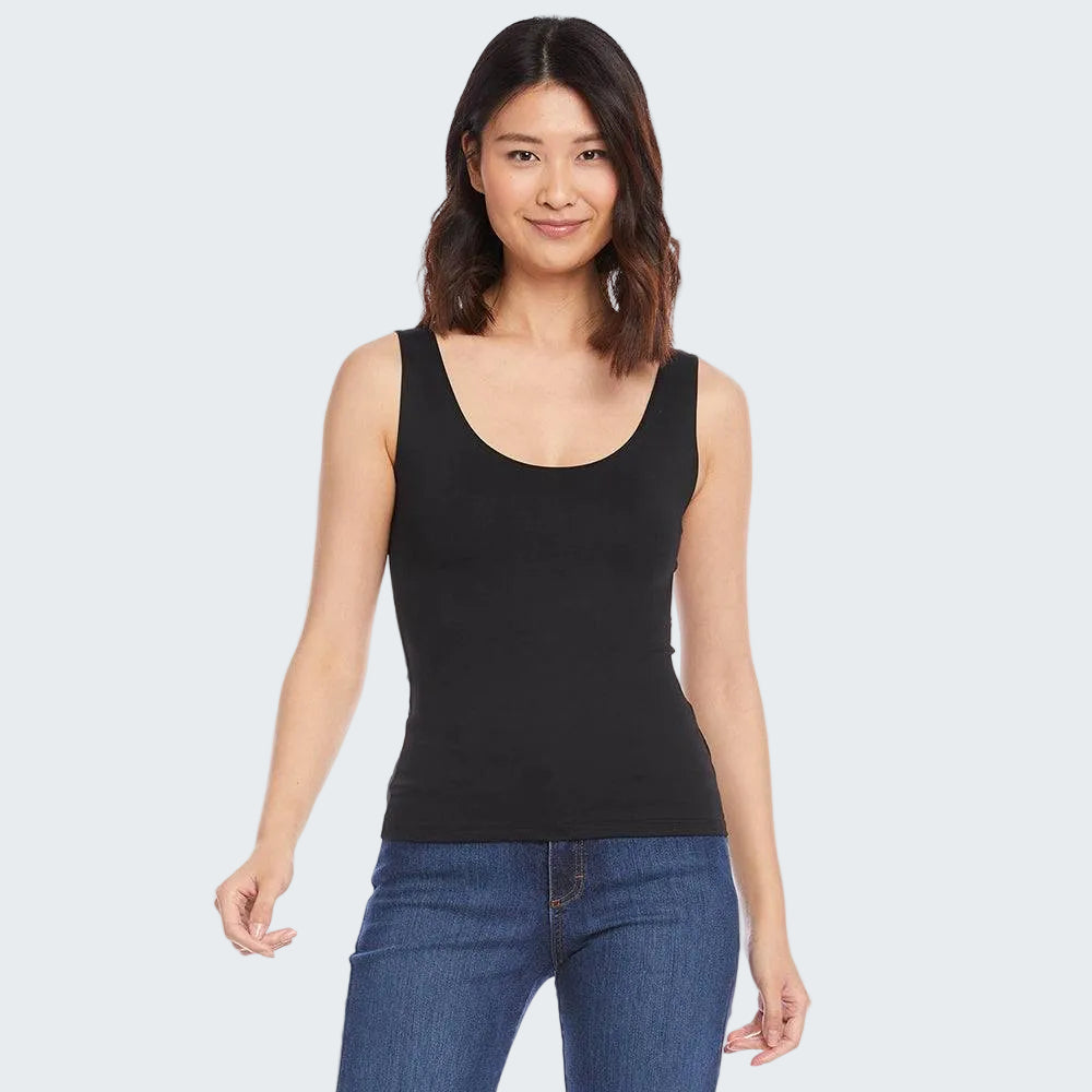 Woman wearing a black tank top and blue jeans on a white background