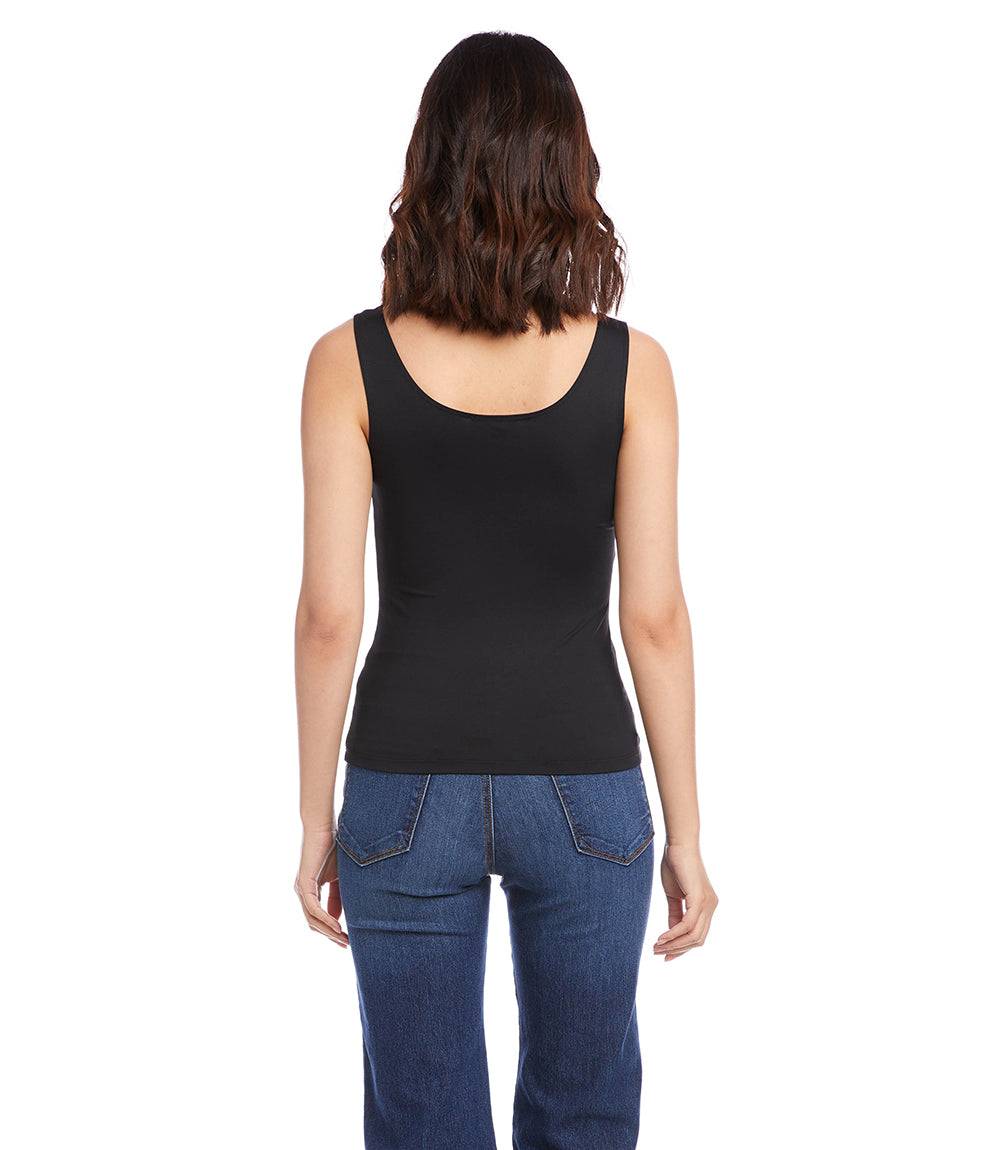 Person wearing a black tank top and blue jeans on a white background