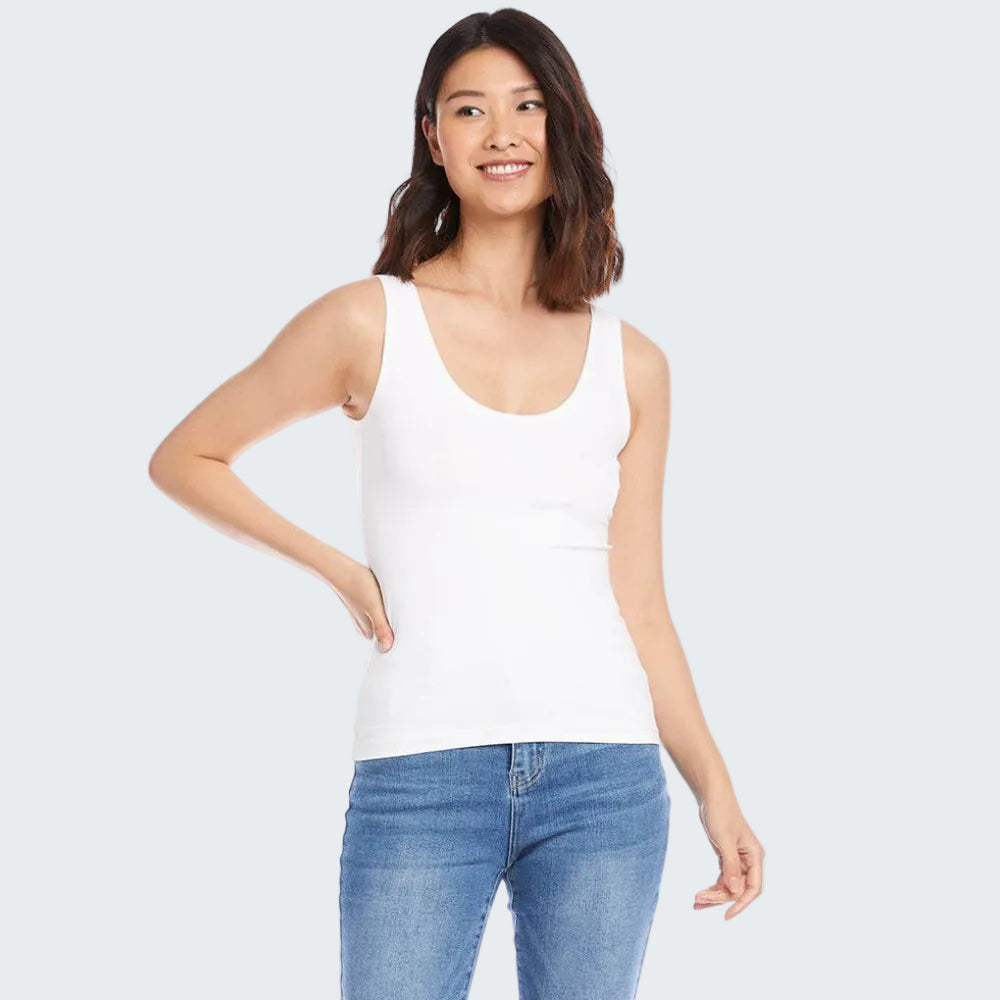 Woman wearing a white tank top and blue jeans on a white background