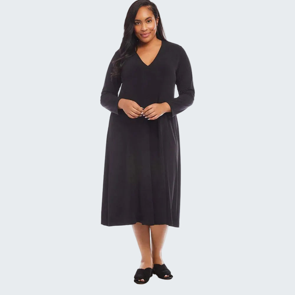 A woman modeling a black long-sleeve midi dress with a V-neckline, standing against a plain white studio background.