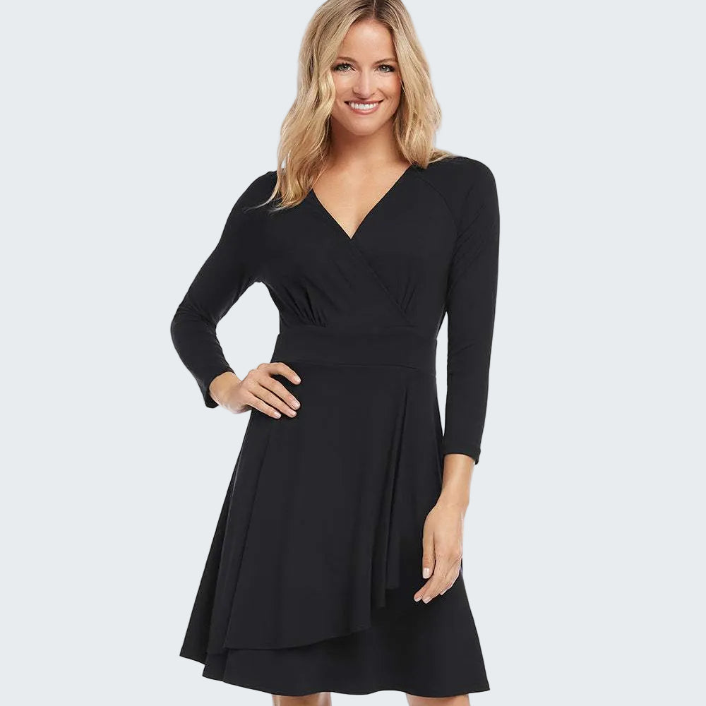 A woman modeling a black long-sleeve V-neck dress with a fitted waist and flared skirt, photographed against a plain white studio background.