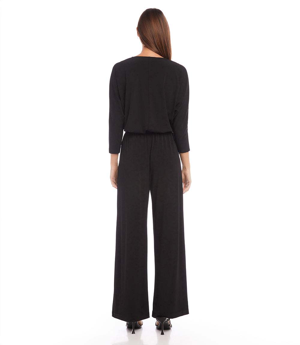 Woman wearing a black outfit with a long cardigan and wide-leg pants on a white background