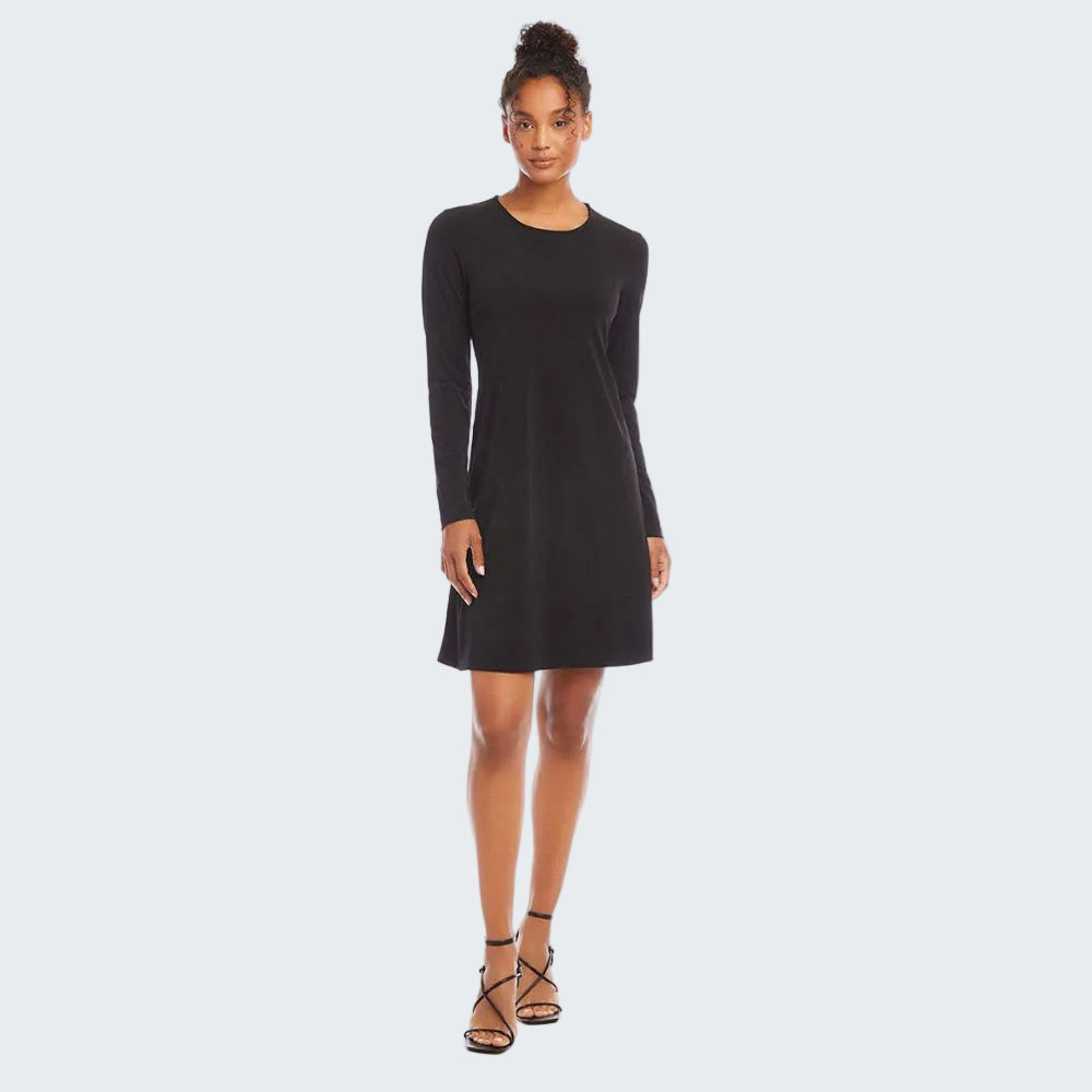 A woman modeling a black long-sleeve shift dress with a crew neck and knee-length hem, paired with black strappy high-heeled sandals, against a solid white background.