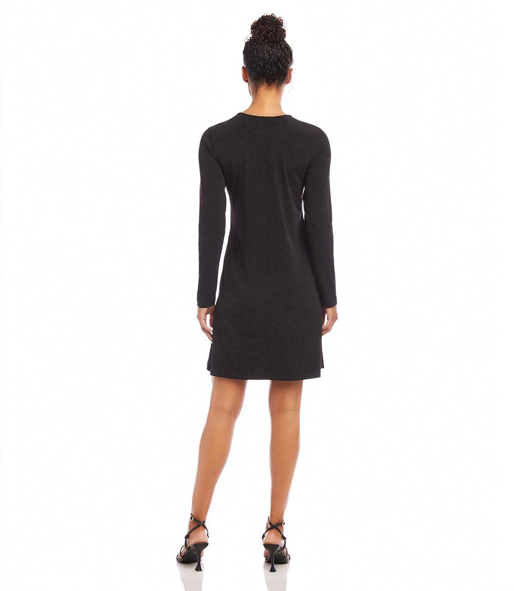 A woman shown from the back wearing a black long-sleeve mini dress and black strappy heels against a plain white background.