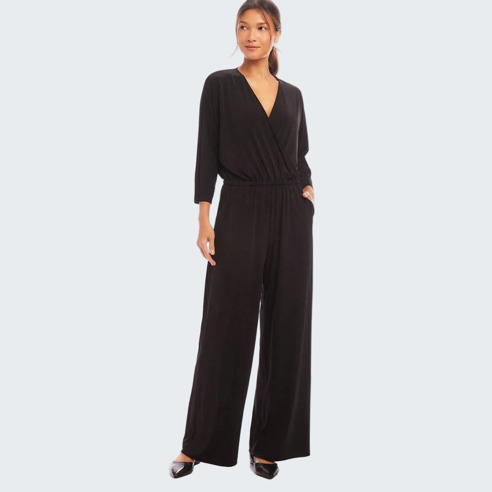 A woman modeling a black wrap-style jumpsuit with three-quarter sleeves and wide legs, standing against a plain white studio background.