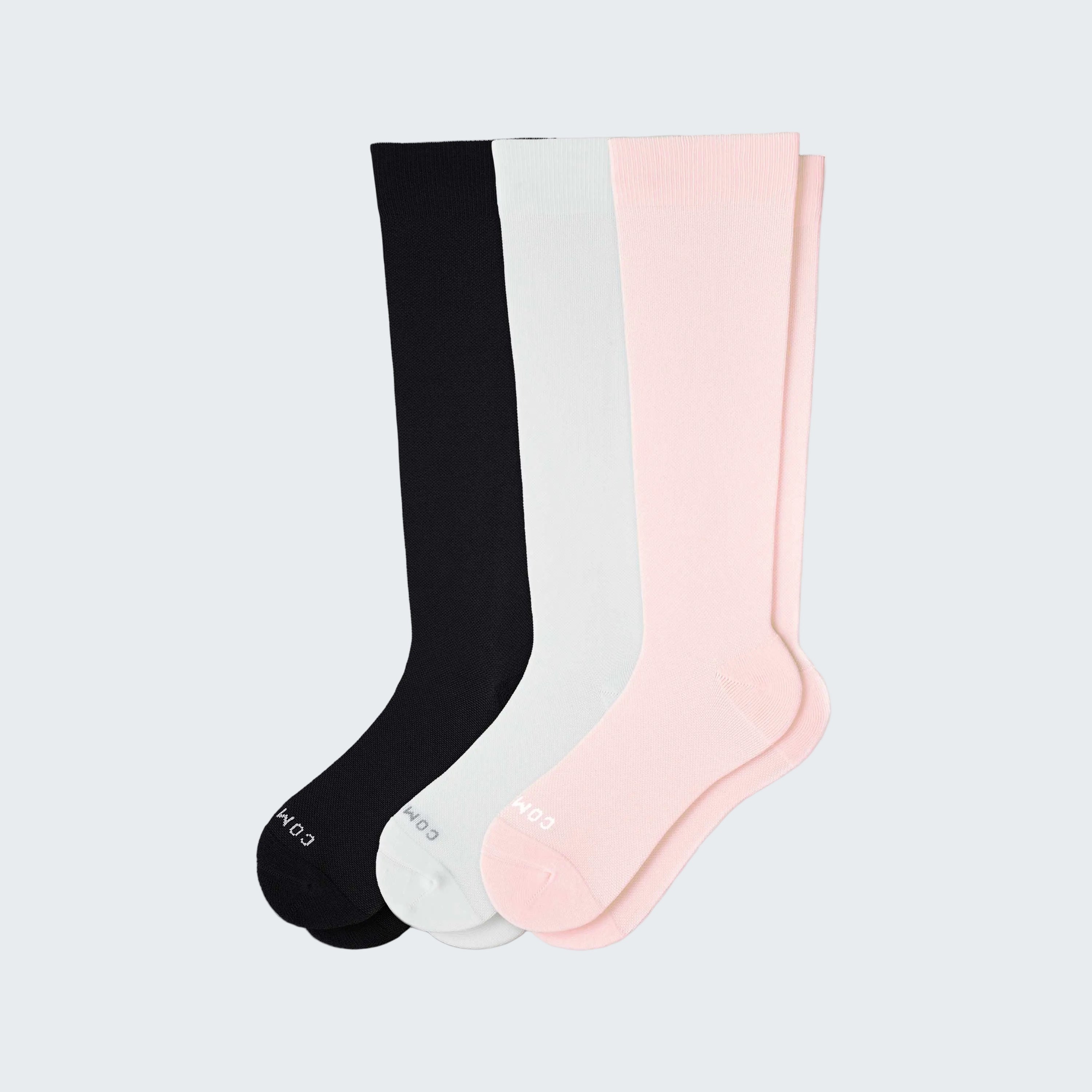 Three pairs of knee-high socks in black, gray, and pink on a white background