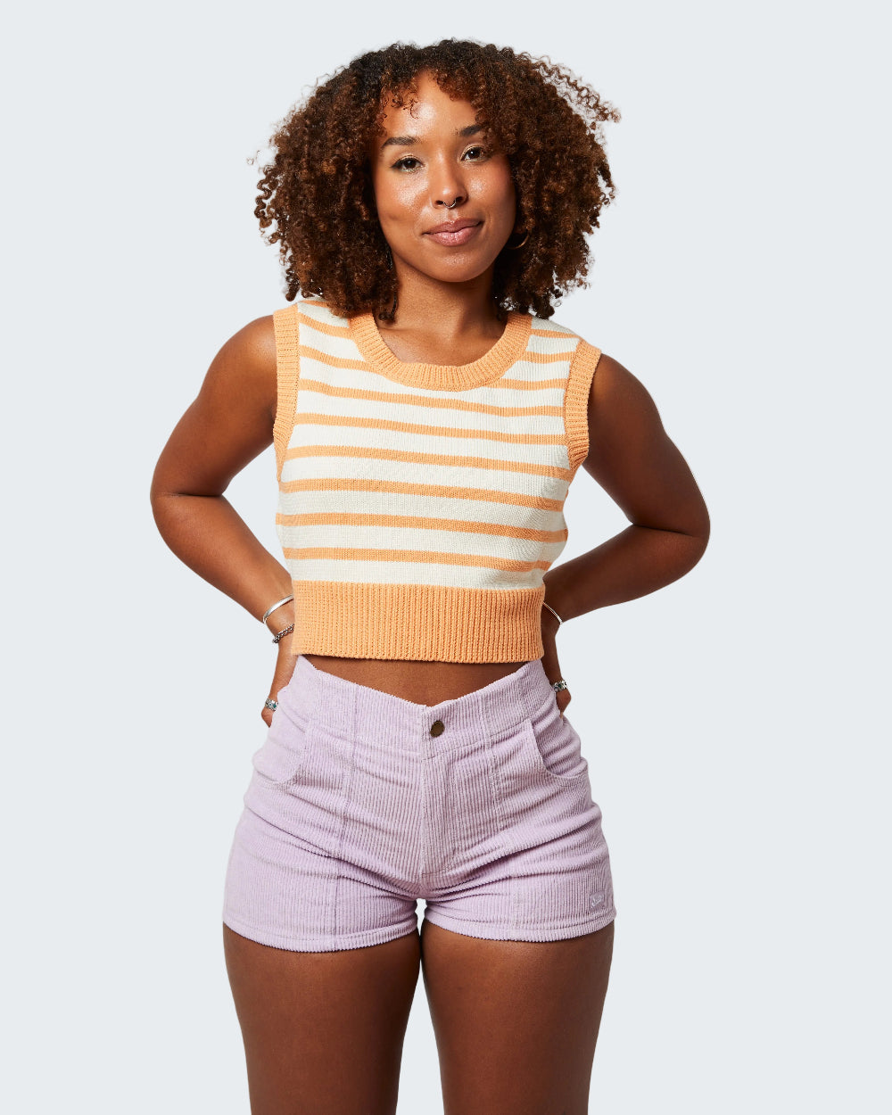 Woman wearing a striped sleeveless top and high-waisted shorts on a white background