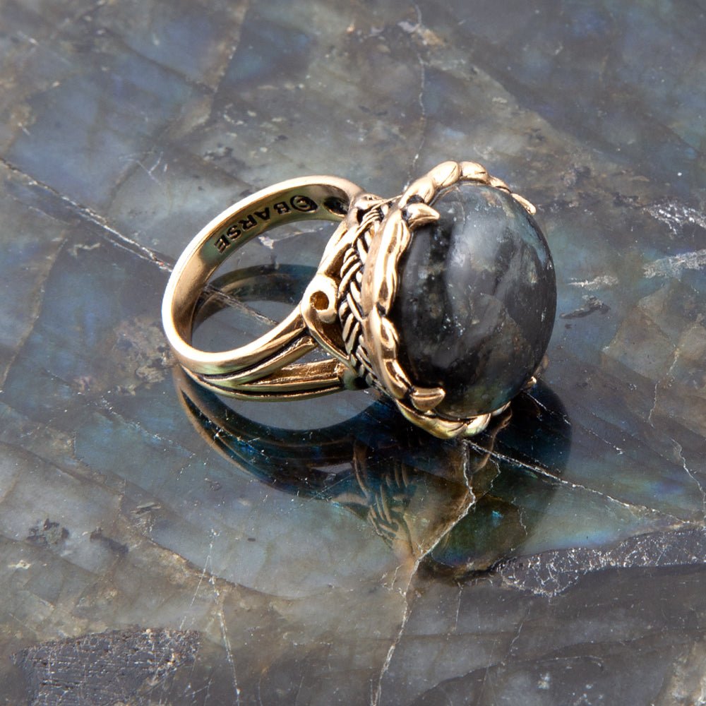 Gold ring with a black stone on a reflective surface