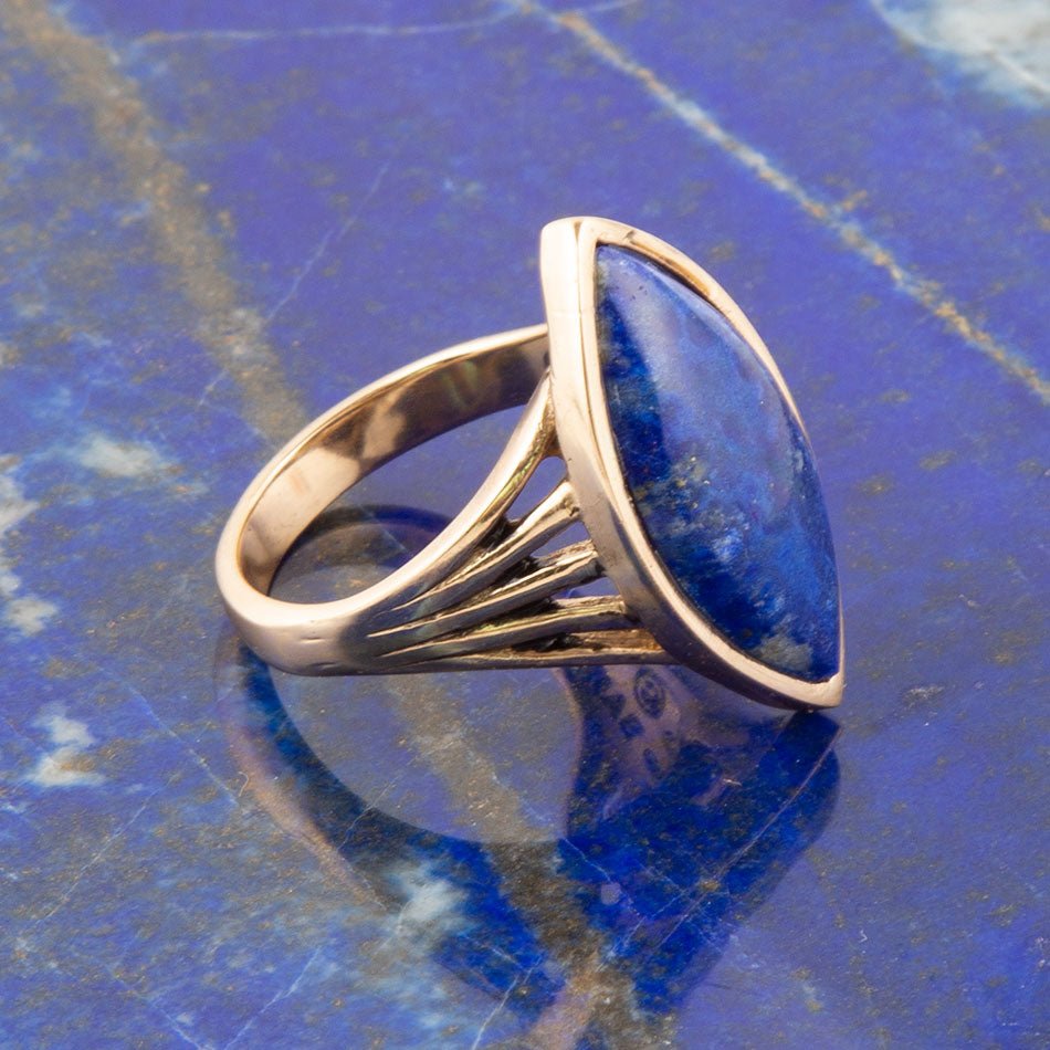 Gold ring with a blue gemstone on a blue textured surface