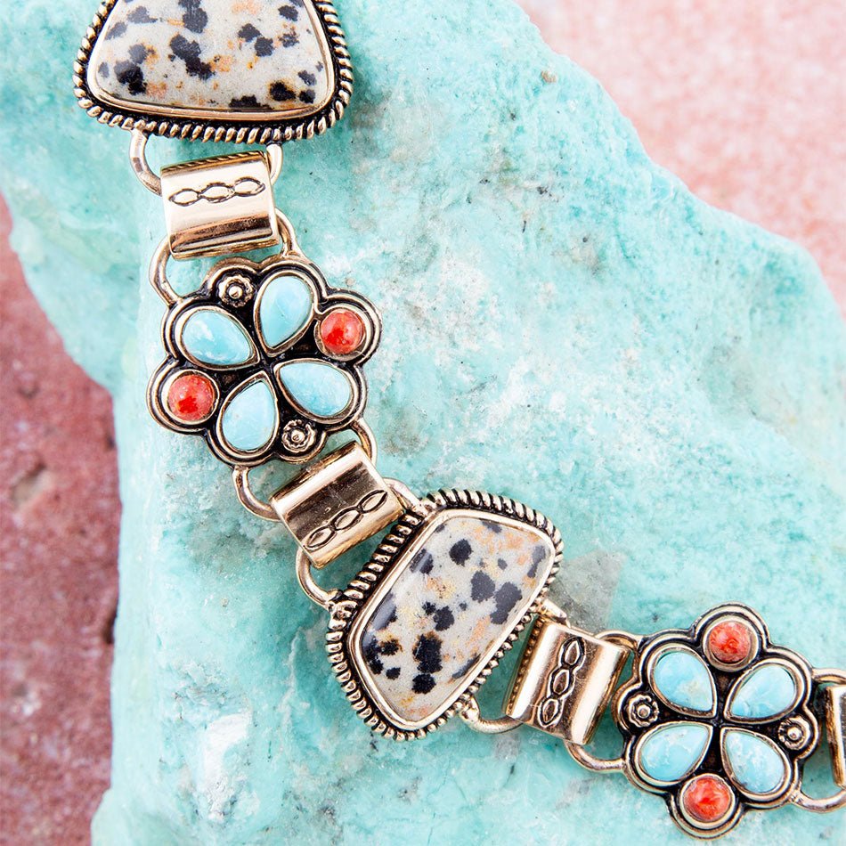 Bracelet with floral designs and natural stone accents on a textured turquoise surface