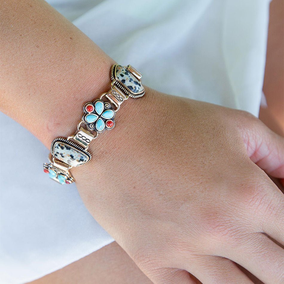 Silver bracelet with floral design on a wrist against a white background